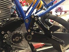 the front end of a blue motorcycle in a shop with other bikes and parts on display