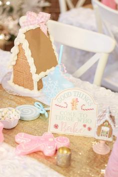 there is a small gingerbread house on the table with other decorations around it and a sign that says good things come to those who bake