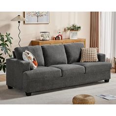 a living room scene with focus on the grey couch and white carpeted flooring