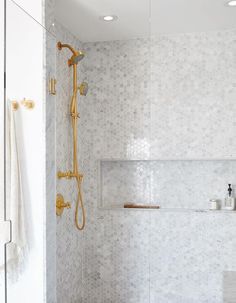 a bathroom with white and gold fixtures in the bathtub, shower head, and towel rack