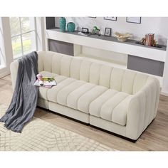 a white couch sitting on top of a hard wood floor next to a rug and window