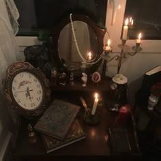 a table topped with a mirror and a clock on top of it next to candles