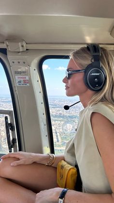 a woman sitting in the cockpit of an airplane wearing headphones and listening to music