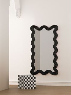 a black and white mirror sitting on top of a wooden floor next to a checkered box