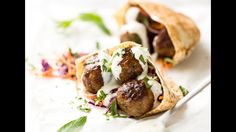 two meatballs on pita bread with white sauce and garnish