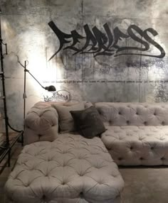 a white couch sitting in front of a wall with graffiti on it's side