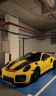 a yellow sports car is parked in a parking garage with blue and white flooring