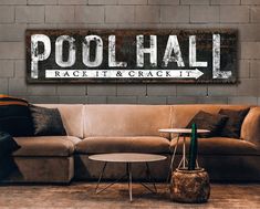 a couch sitting in front of a brick wall with the word pool hall on it