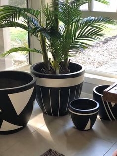 three black and white planters sitting next to a window