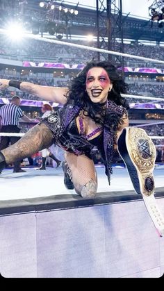 a woman with tattoos on her arms and legs, holding a wrestling belt in the air