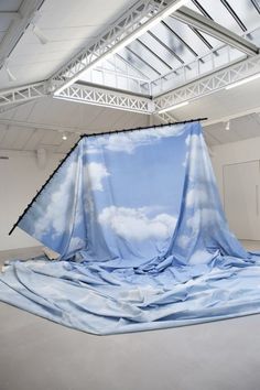 an advertisement for the exhibition latifa echakch, with blue sky and clouds draped over it