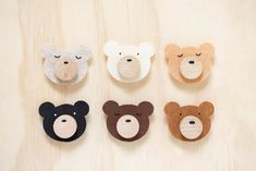 four wooden bear magnets with faces on them sitting on top of a wood table