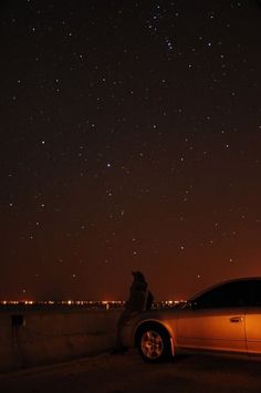 a car parked on the side of a road at night with stars in the sky