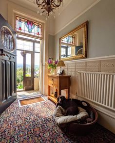 a dog is laying in his bed on the floor next to an open door with a stained glass window