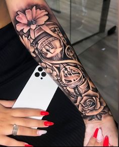 a woman's arm with a clock and flowers tattoo on her left arm, next to a cell phone