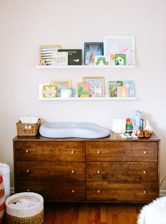 a baby's room with wooden furniture and pictures on the wall, including a crib