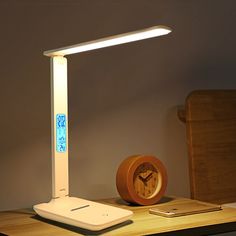 a lamp that is on top of a desk next to a cell phone and a clock