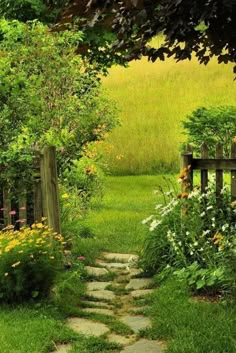 a stone path leading to a wooden bench in the middle of a lush green garden