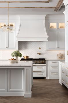 a large kitchen with white cabinets and marble counter tops, gold accents on the ceiling