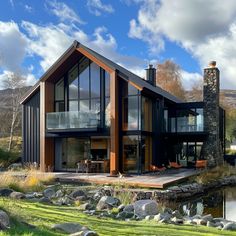 a large house sitting on top of a lush green field next to a lake and forest