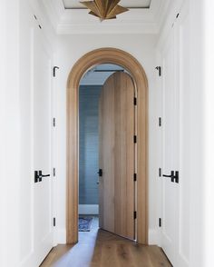 an arched wooden door in a white hallway