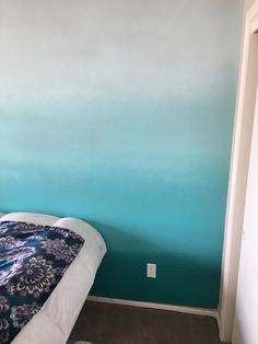 a bed sitting next to a blue wall in a bedroom