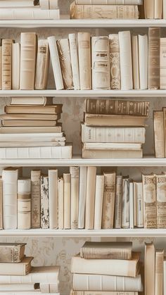 many books are lined up on shelves in a room with wallpaper and floral designs