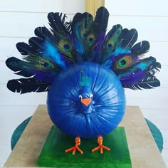 there is a fake peacock sitting on top of a blue ball with feathers around it