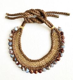 a close up of a bracelet on a white surface with brown cords and glass beads