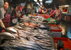 a woman standing in front of a table filled with fish