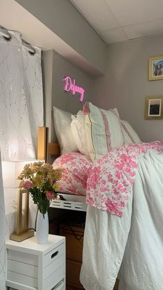 a bed with pink and white comforter next to a night stand in a bedroom