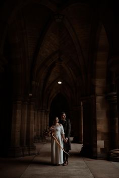 a man and woman are standing in an old building holding a cane with the light shining on them