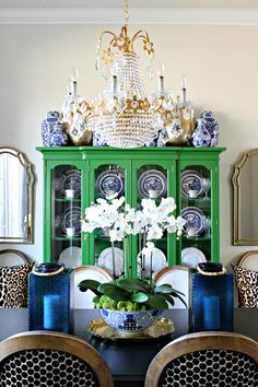 a dining room table with blue and white china cabinet in the center, surrounded by leopard print chairs