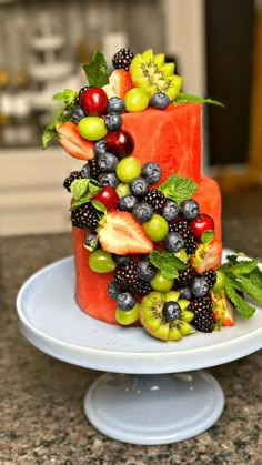 a cake made out of fruit sitting on top of a white plate in a kitchen