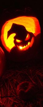 two pumpkins carved to look like animals in the dark with their faces lit up