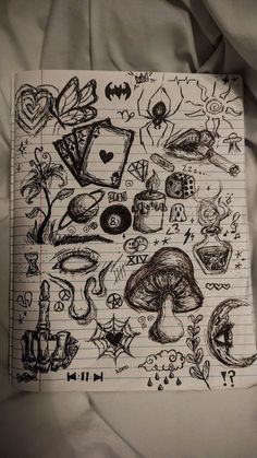 a notebook with drawings on it sitting on top of a bed next to a sheet of paper