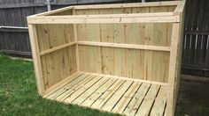 a wooden shelf sitting on top of a grass covered field in front of a fence