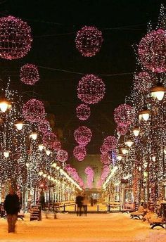 people are walking down the street covered in christmas lights