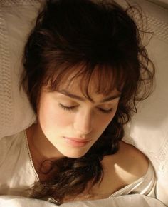 a woman laying in bed with her eyes closed