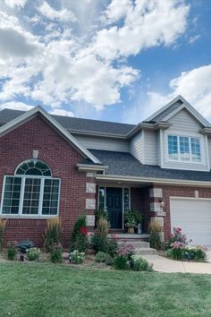 a brick house with green grass and flowers in the front yard