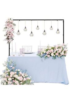 a table topped with flowers and candles next to a blue table cloth filled with white and pink flowers