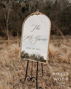 a sign in the middle of a field with trees and grass behind it that says the mr and mrs