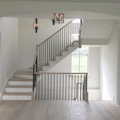 an empty room with white walls and wood flooring, stairs leading up to the second floor