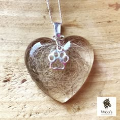 a heart shaped glass pendant with a dog's paw on it