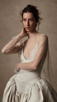 a woman in a white dress posing with her hands on her chin and wearing a veil