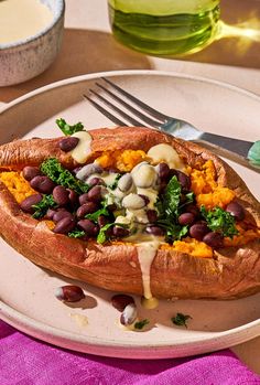 a white plate topped with a baked potato covered in beans and greens