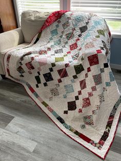 a white couch sitting next to a window covered in a quilt