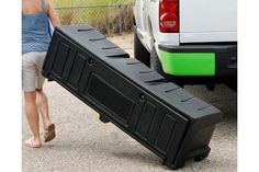 a woman carrying a large black object on the back of a truck