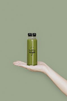 a person's hand holding a green smoothie bottle