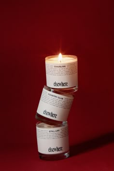 three candles stacked on top of each other in front of a red background with the candle lit